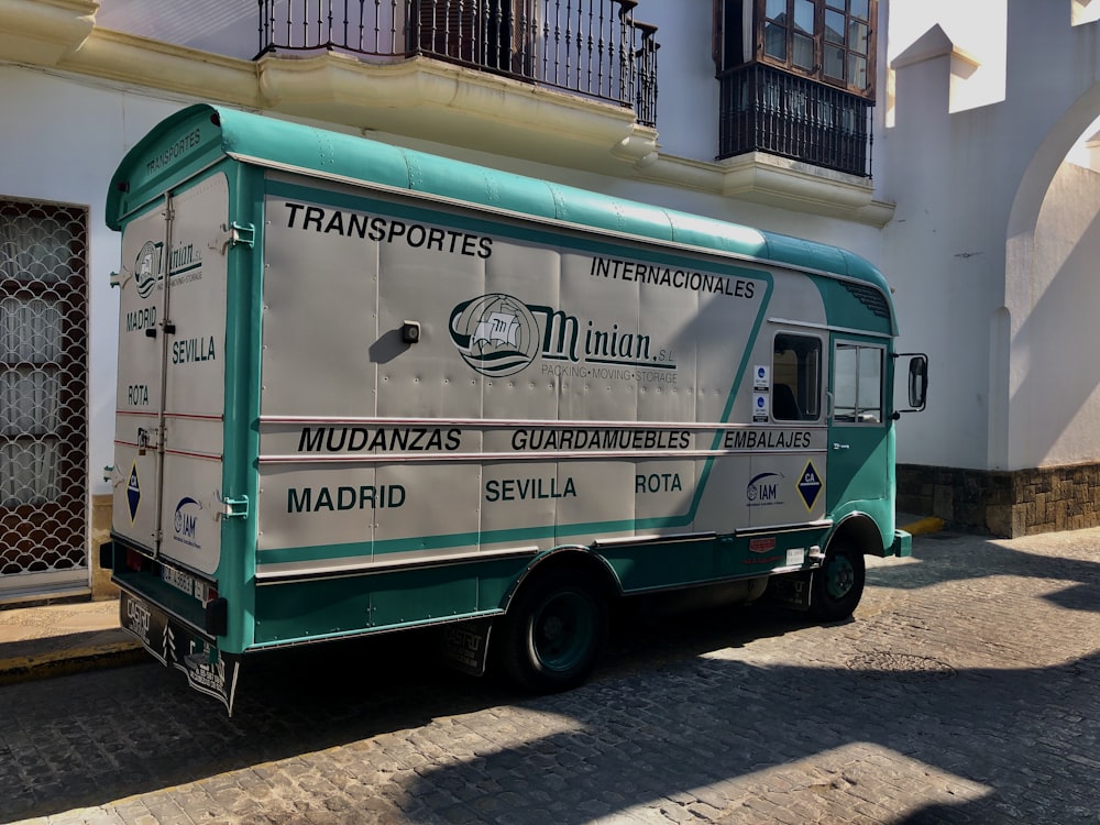 a green and white truck parked in front of a building