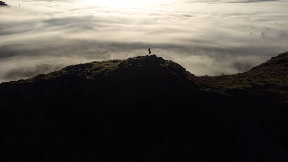 a person standing on top of a mountain surrounded by clouds