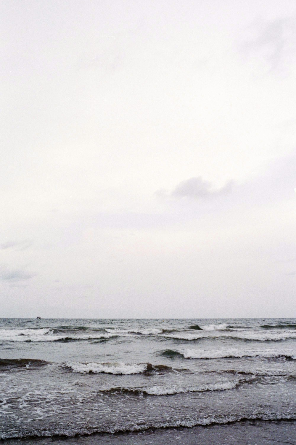 a man walking across a beach next to the ocean