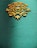 An ornate, symmetrical wooden decoration with intricate patterns sits on a textured teal background. The design features swirling lines and curves, giving it an elegant and artistic appearance.