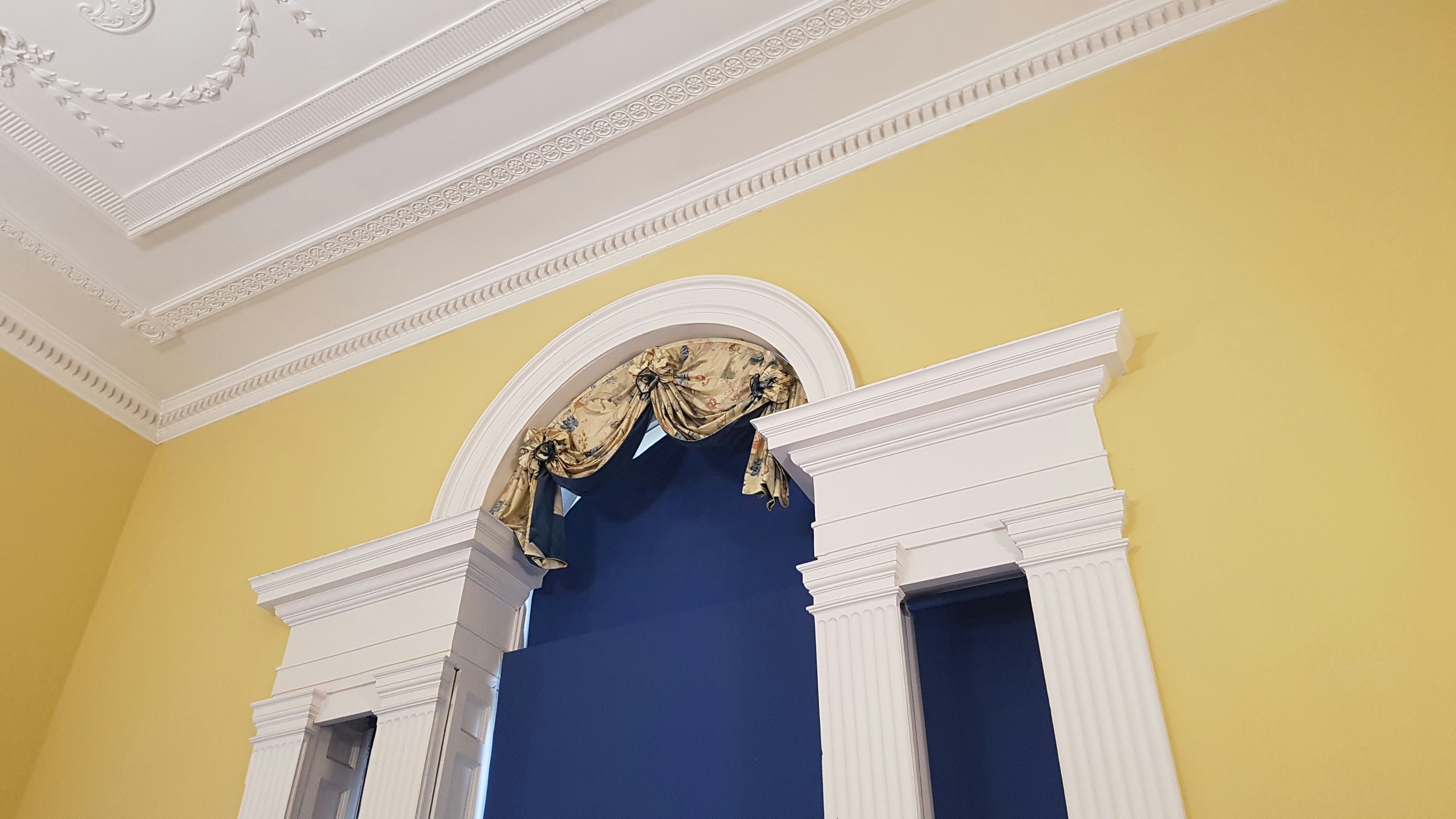 a blue and yellow room with a window and a curtain