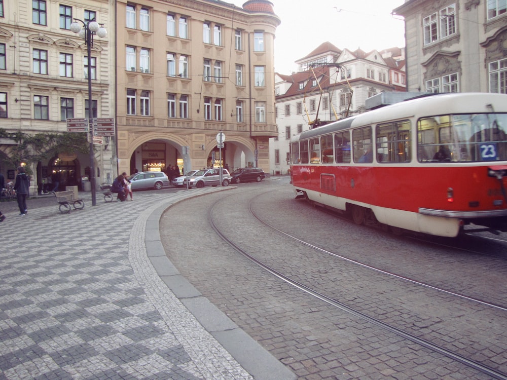 a red and white trolley on a city street