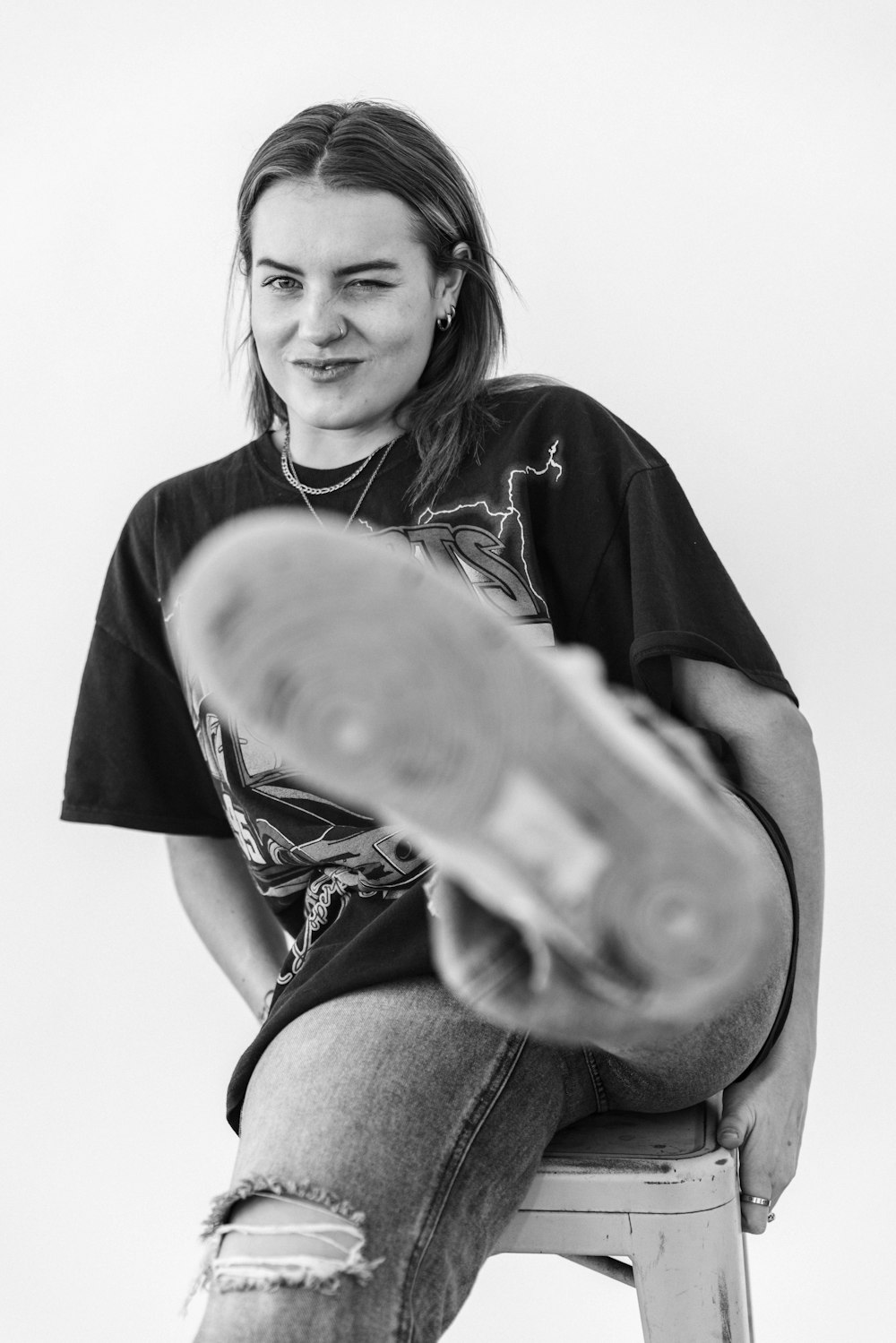 a woman sitting on a stool holding a skateboard