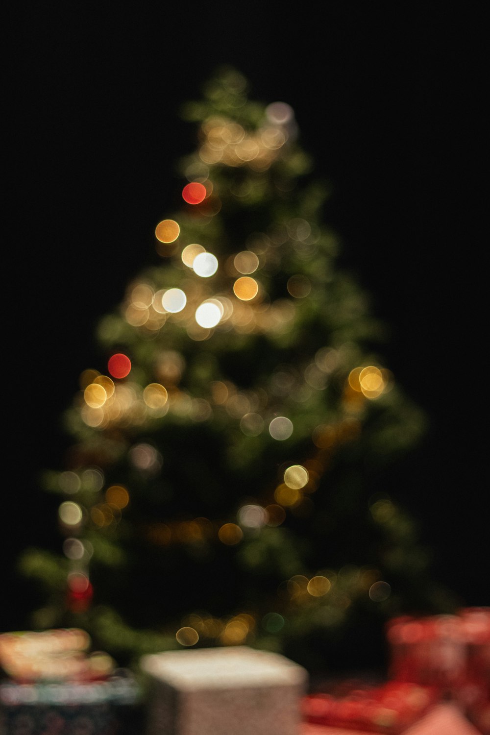 a small teddy bear sitting in front of a christmas tree