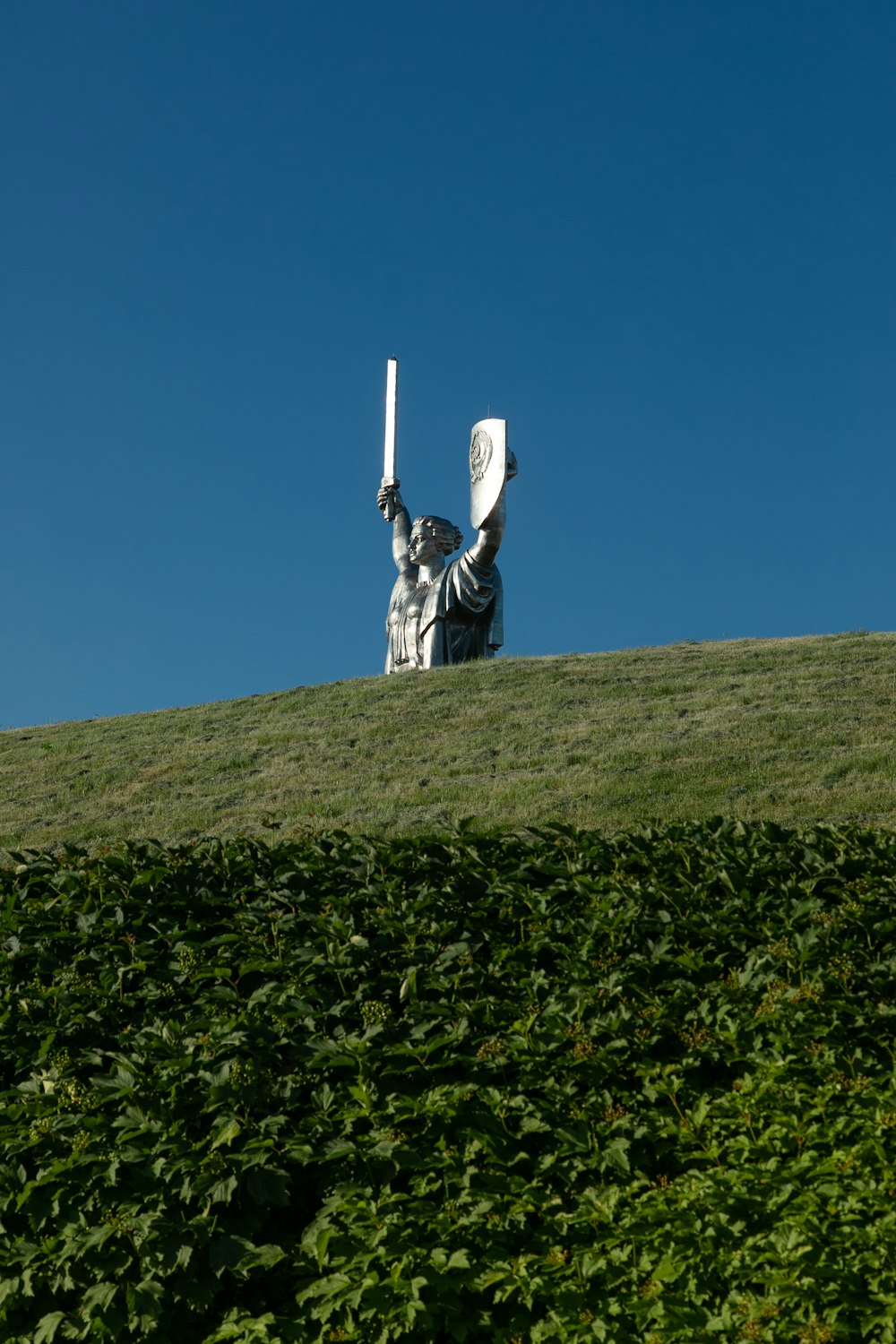 a statue of a person holding a frisbee on top of a hill