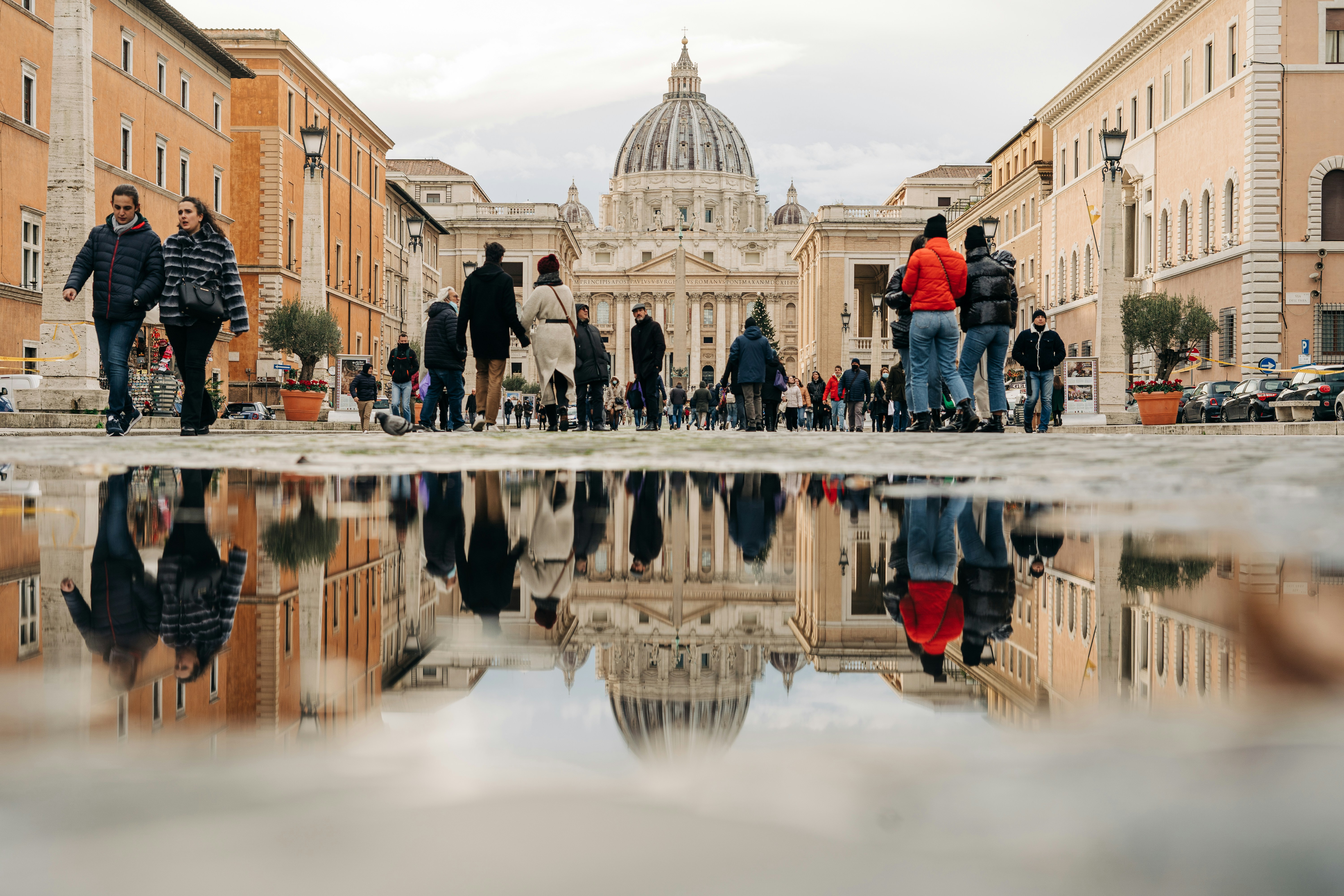 a group of people walking down a street next to tall buildings, Christmas at the Vatican