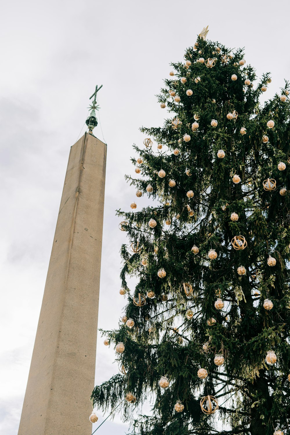 a large christmas tree next to a tall monument