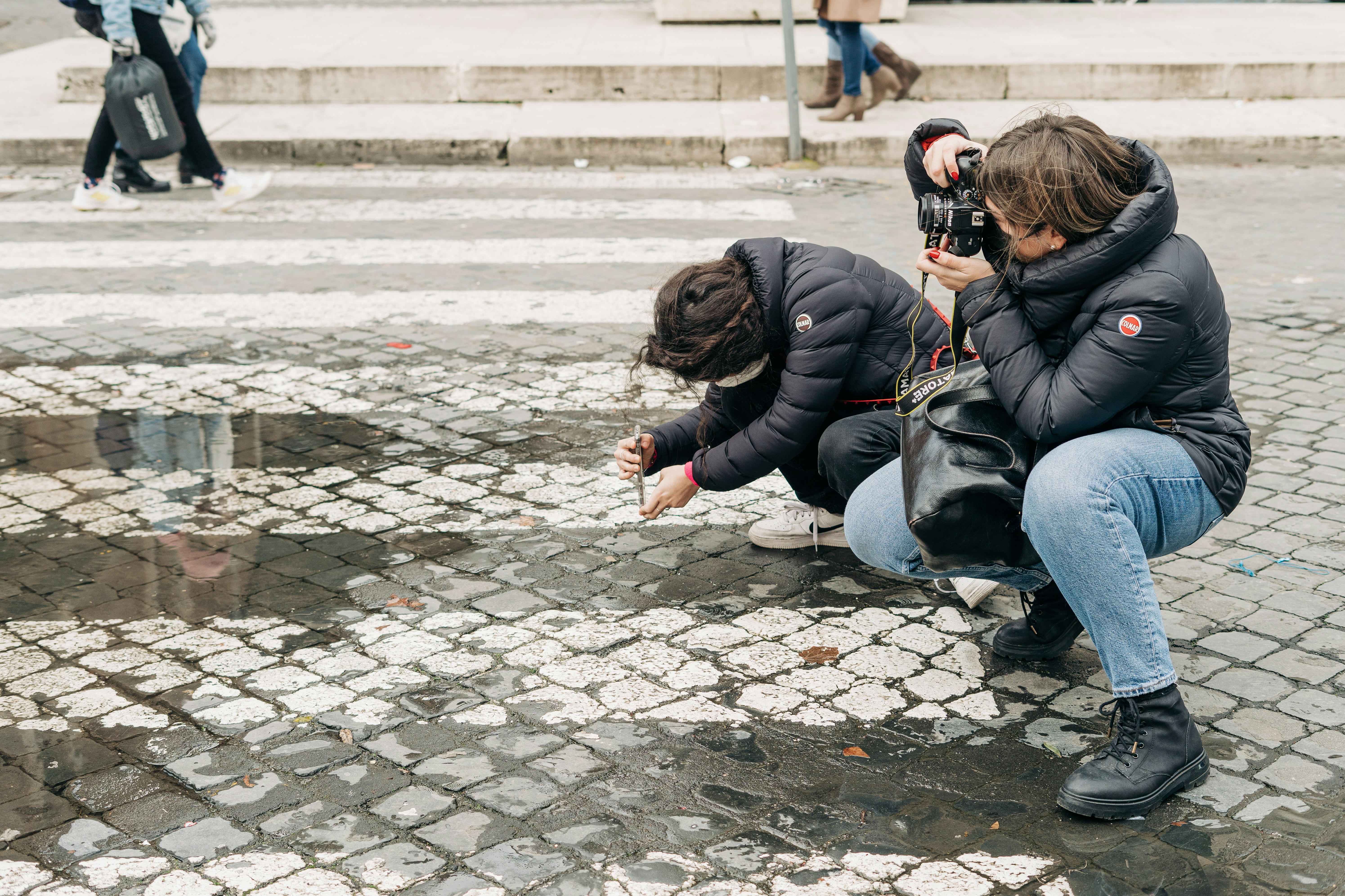 a woman taking a picture of another woman on the street, Two female street photographers in action in Rome, Italy