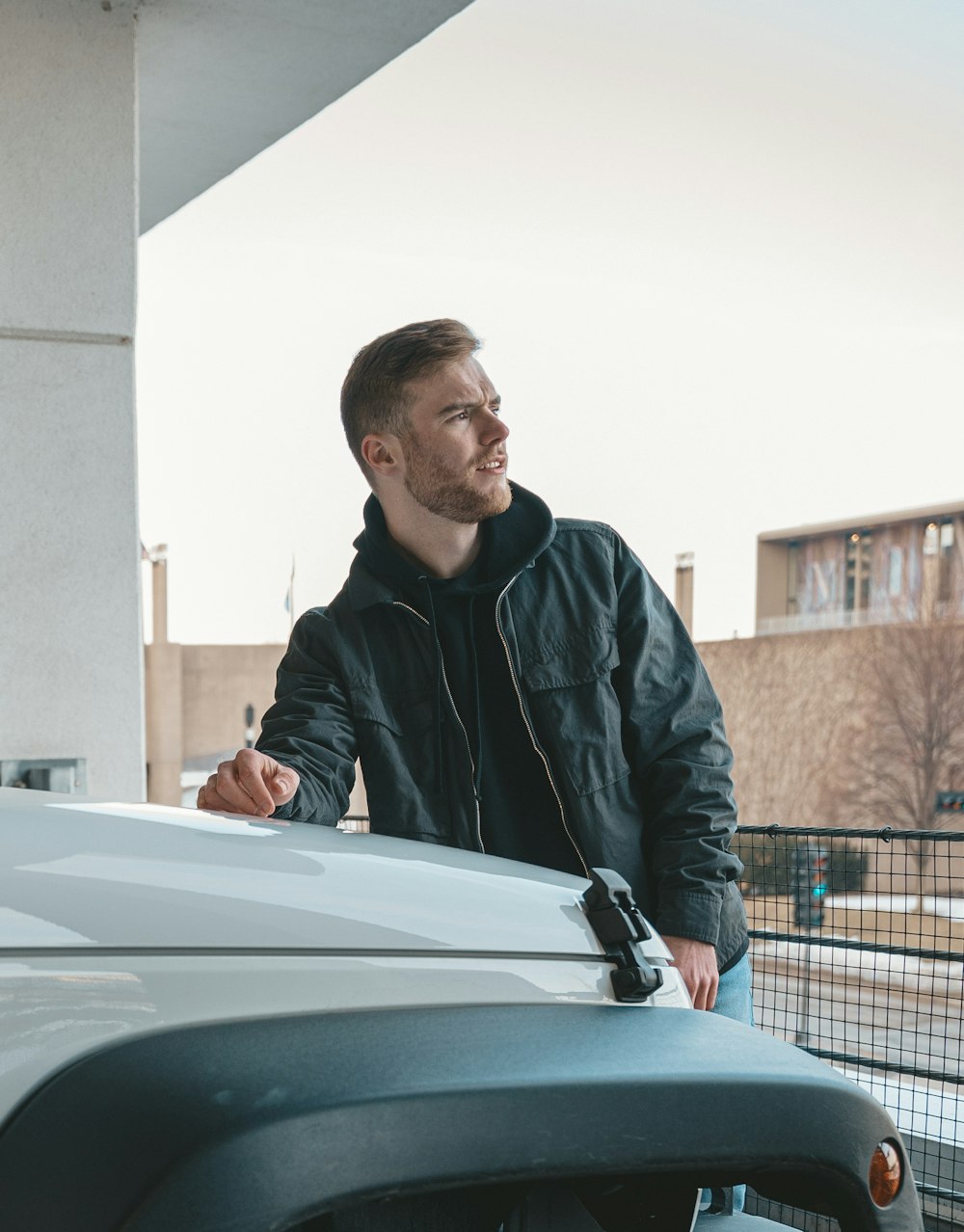 a man standing next to a car with headphones on