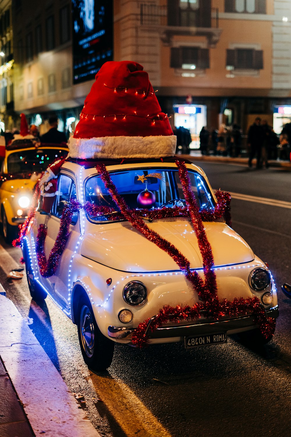 a car with a christmas hat on top driving down the street