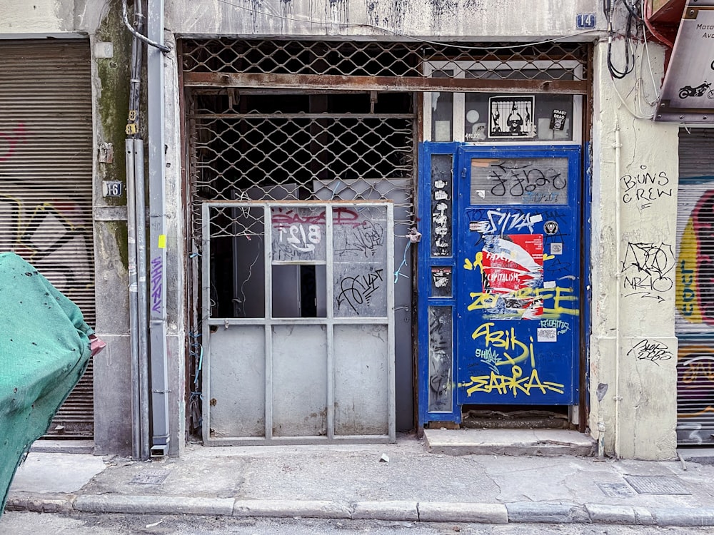 a blue door with graffiti on the side of a building