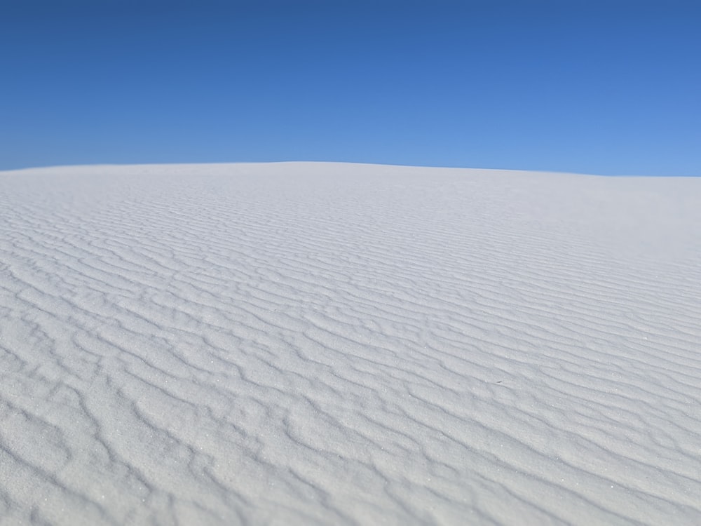 a white sand dune with a blue sky in the background