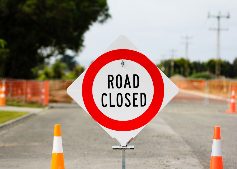 a road closed sign sitting on the side of a road