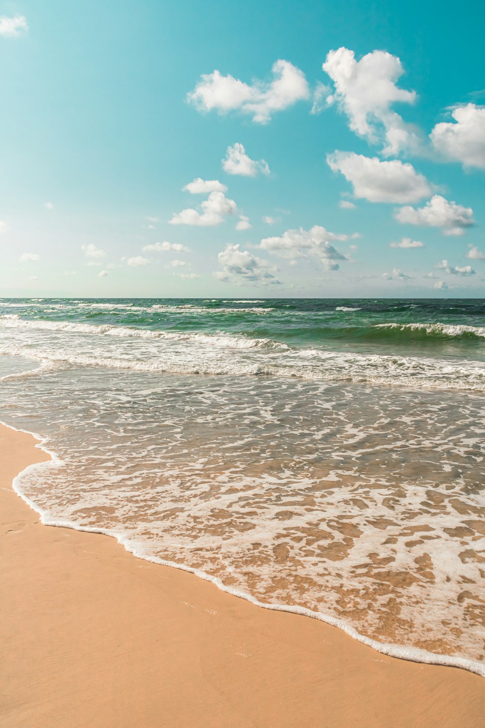 une plage de sable avec des vagues qui arrivent sur le rivage