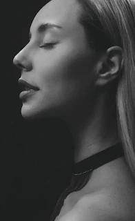 A serene portrait of Rina Kelly softly lit against a minimalist white backdrop, embodying quiet confidence.