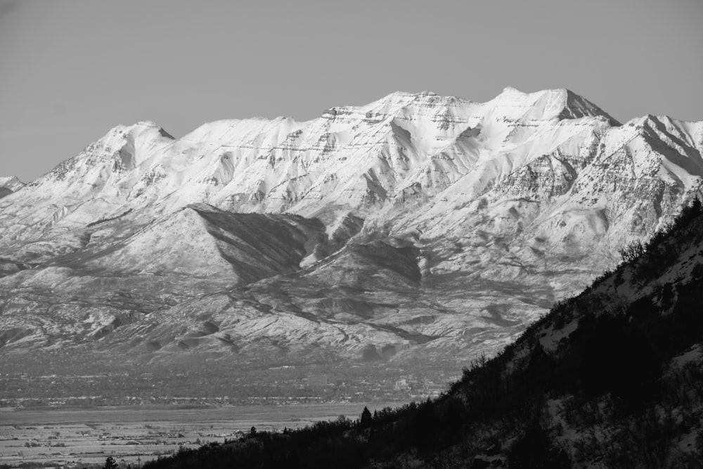 a snow covered mountain range with trees in the foreground