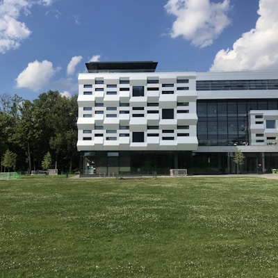 a large white building sitting on top of a lush green field