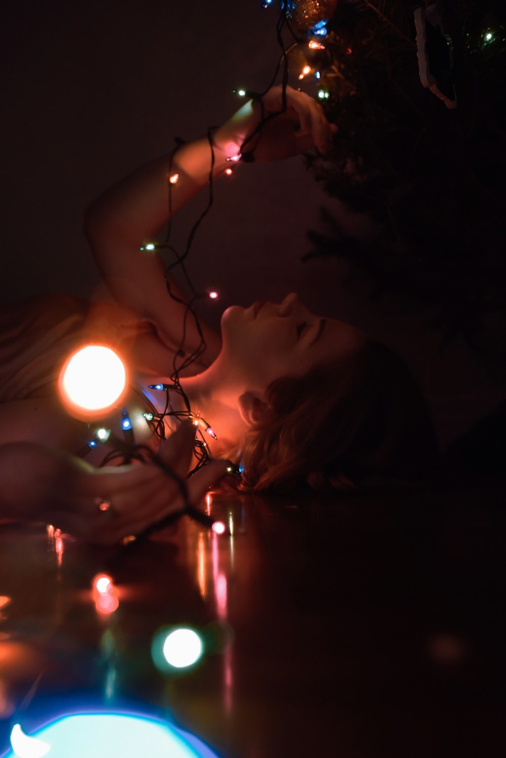 a woman laying on a table next to a christmas tree