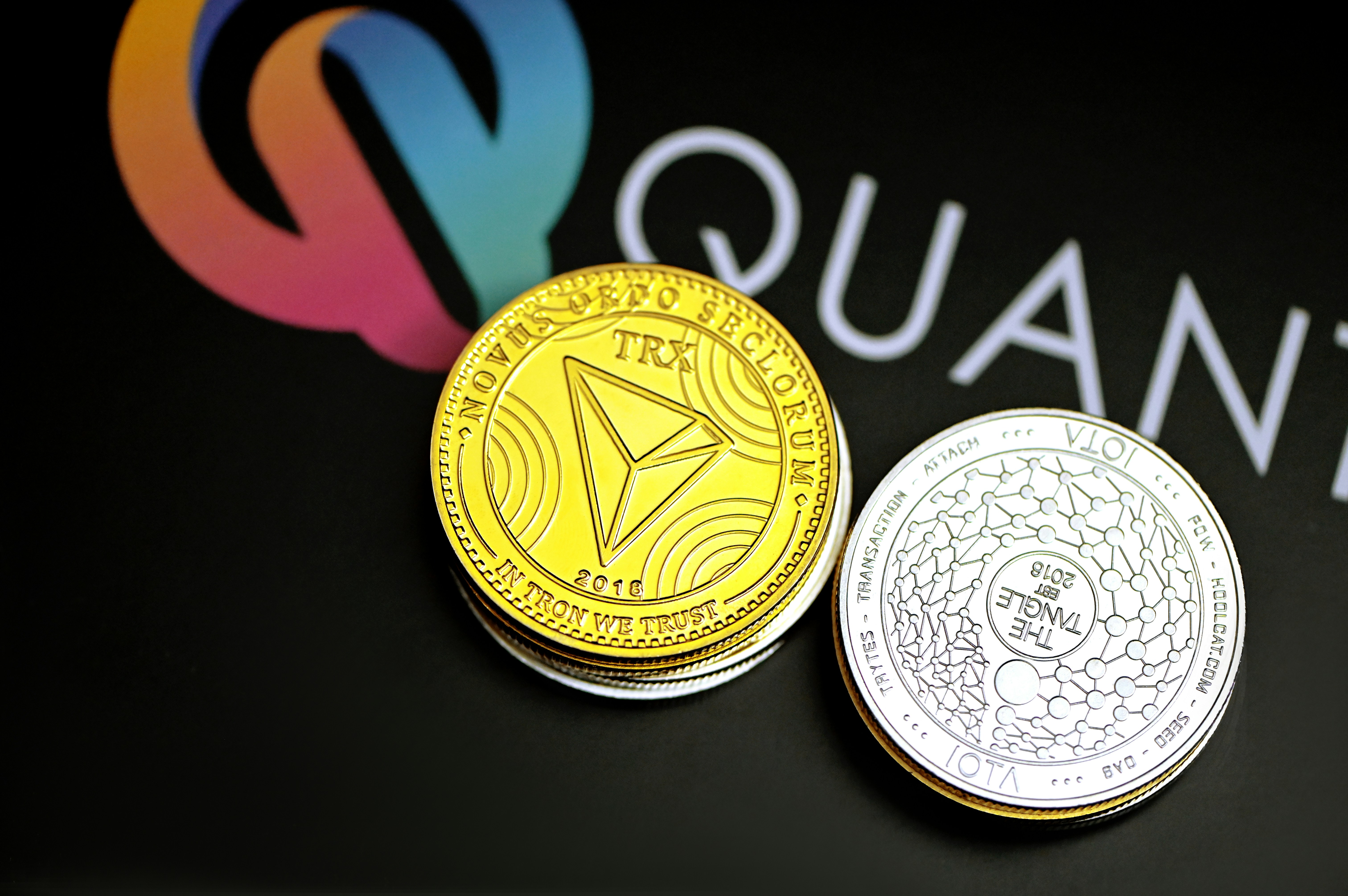 TRON coin and IOTA coin placed on the Quantitatives background