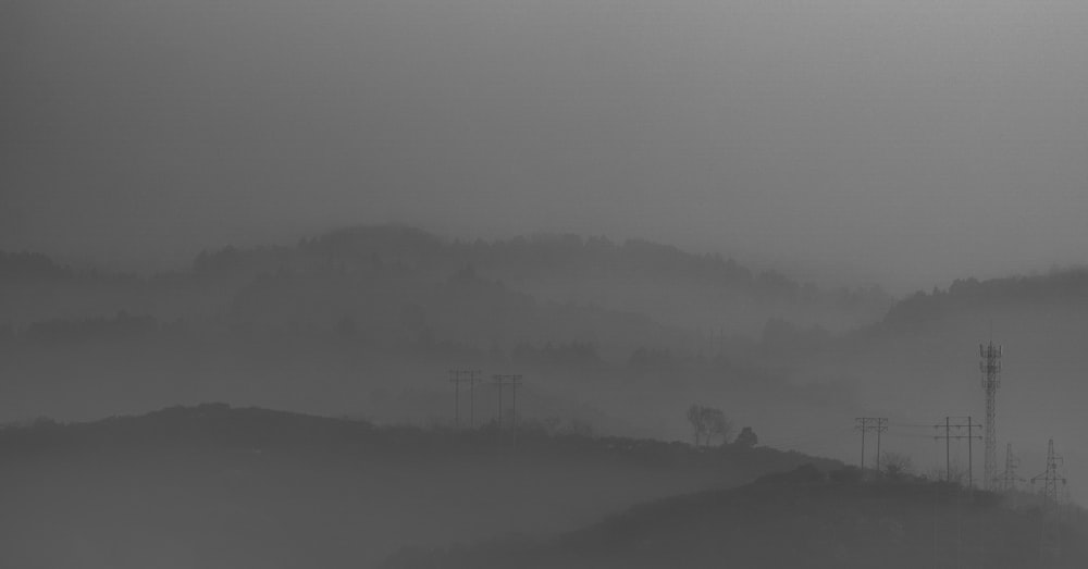 a black and white photo of a foggy hillside