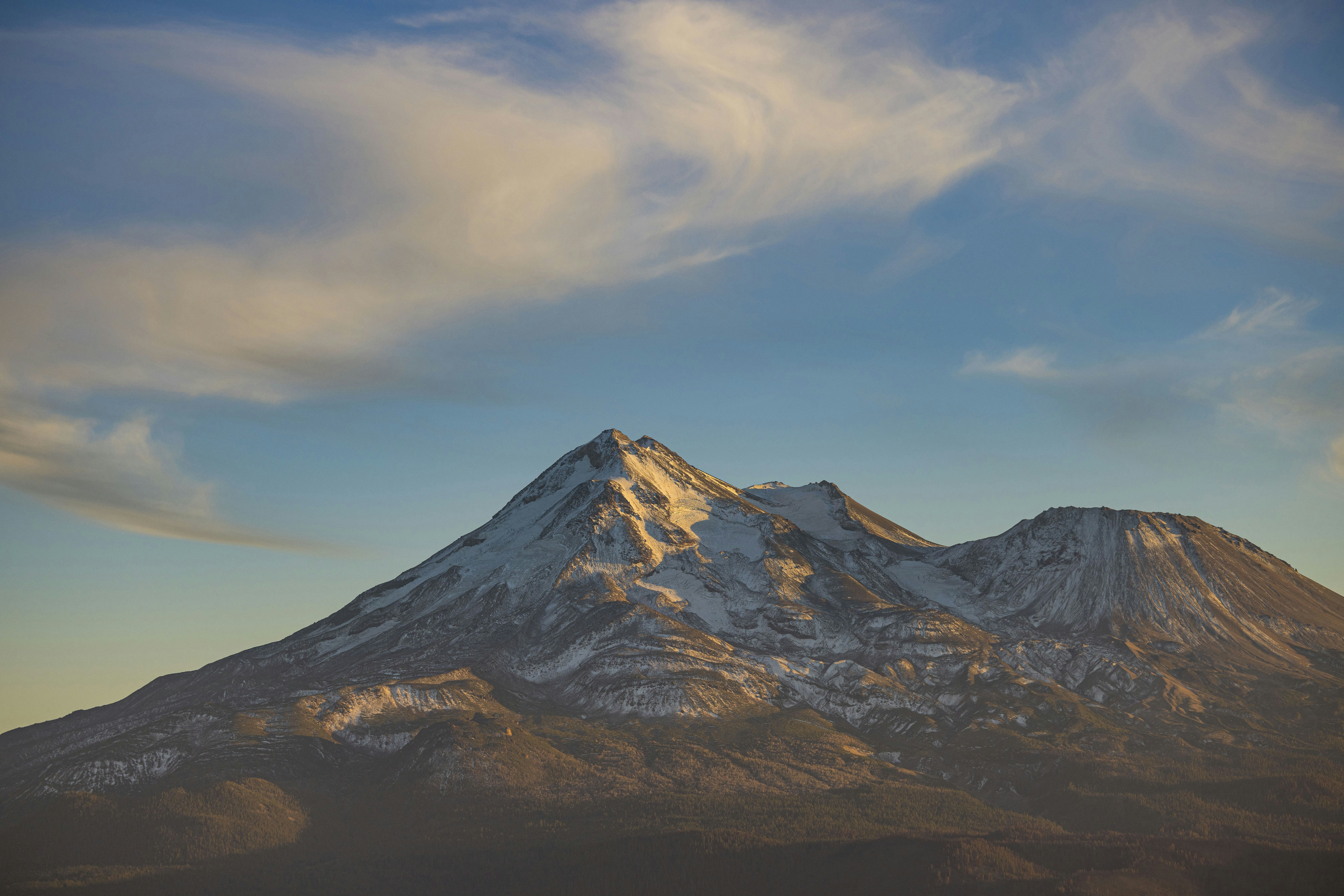 a snow covered mountain with clouds in the sky