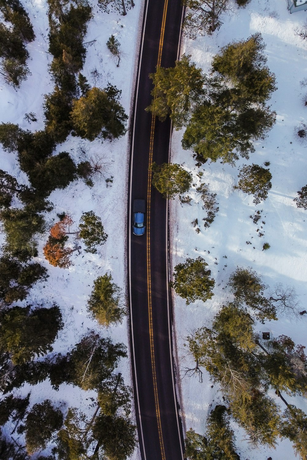 an aerial view of a car driving on a snowy road