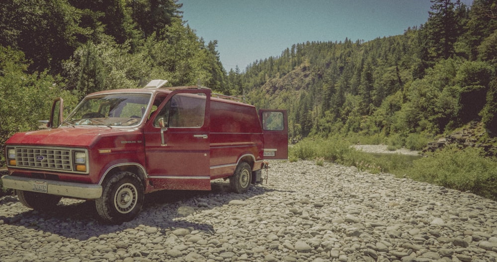 a red van parked on the side of a rocky road