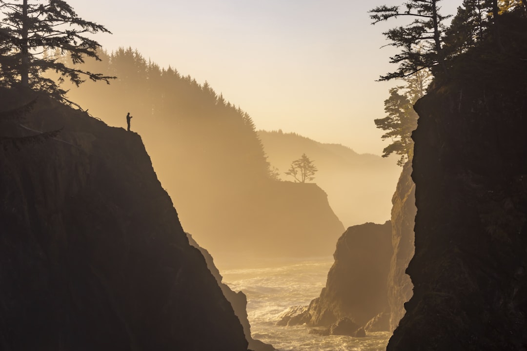 a person standing on a cliff overlooking the ocean, adventure travel