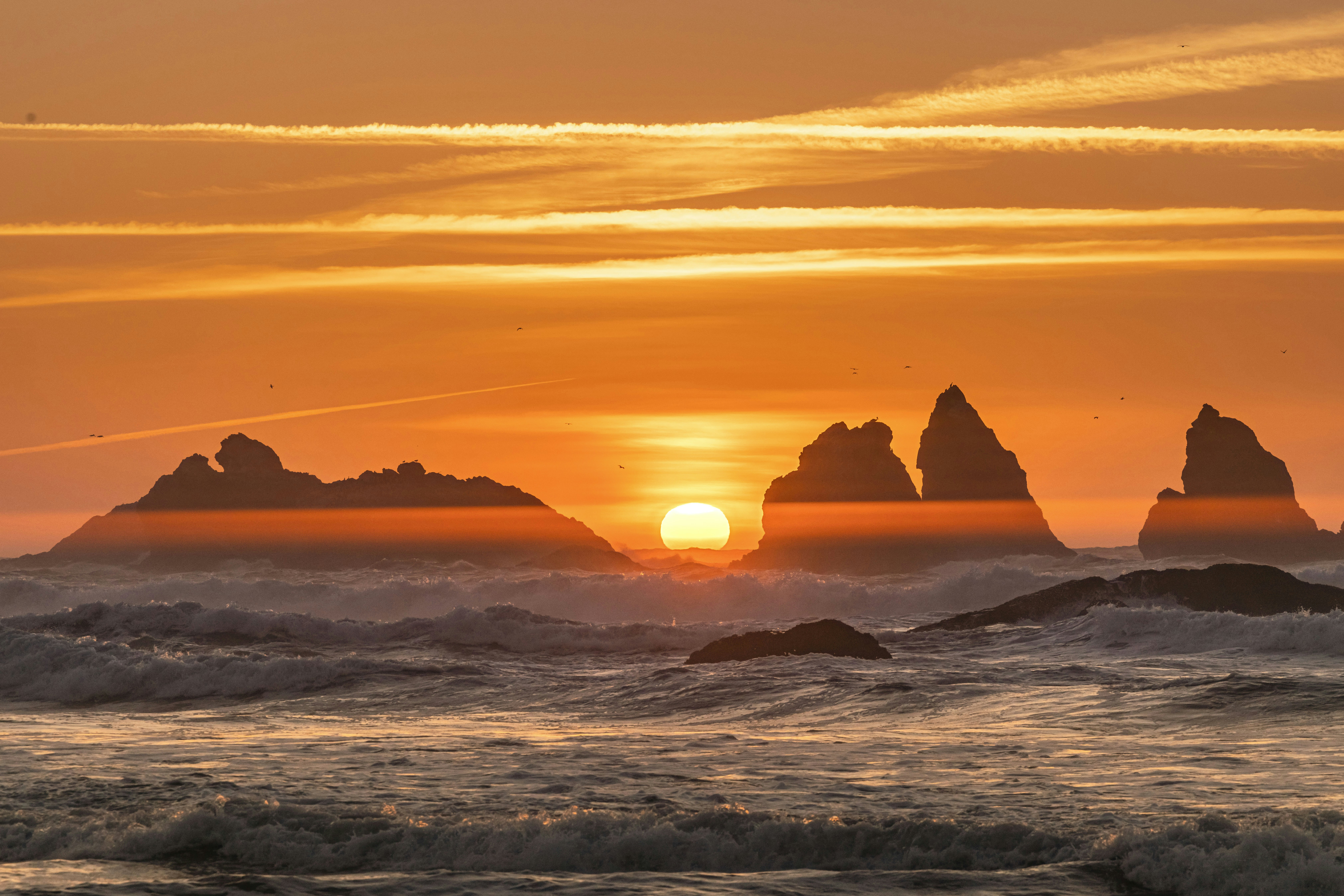 the sun is setting over some rocks in the ocean
