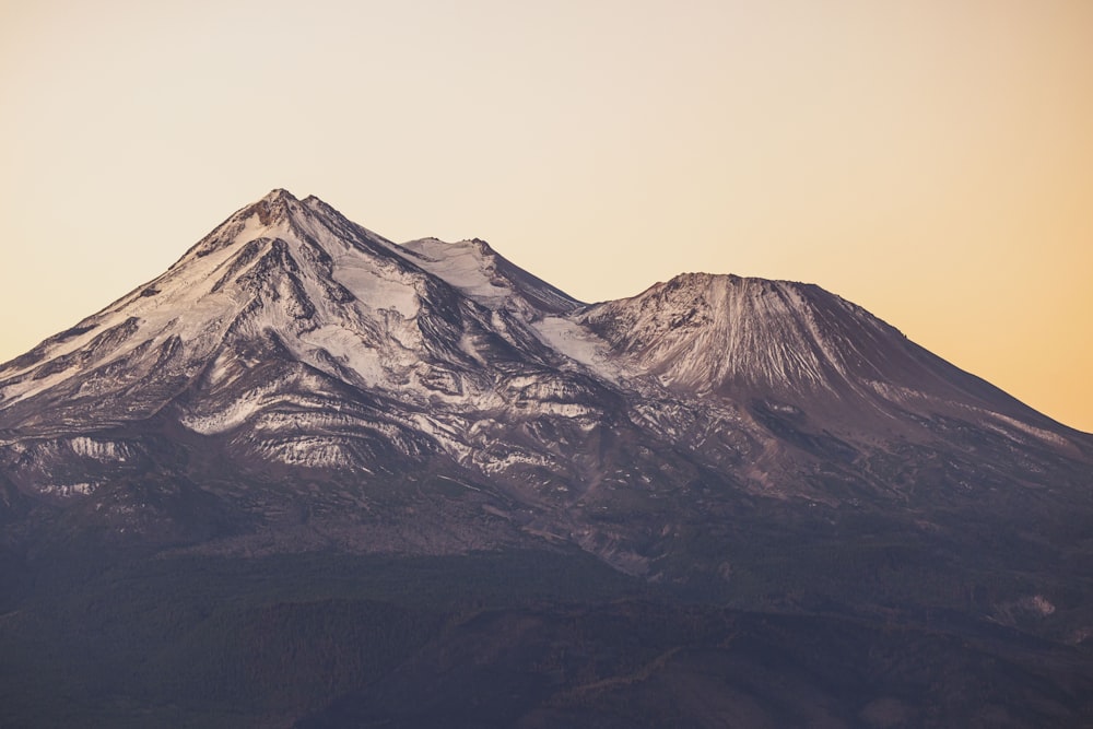 a snow covered mountain in the distance at sunset
