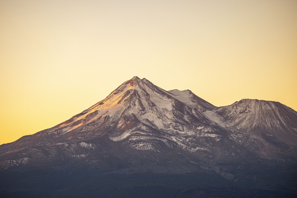 a snow covered mountain with a yellow sky in the background