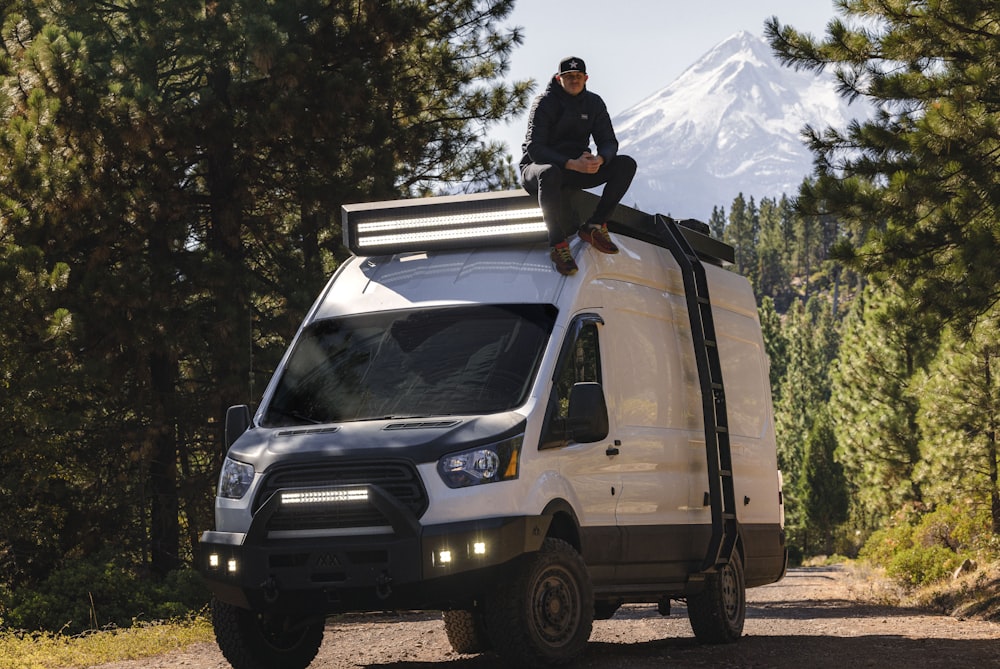 a man sitting on top of a white van