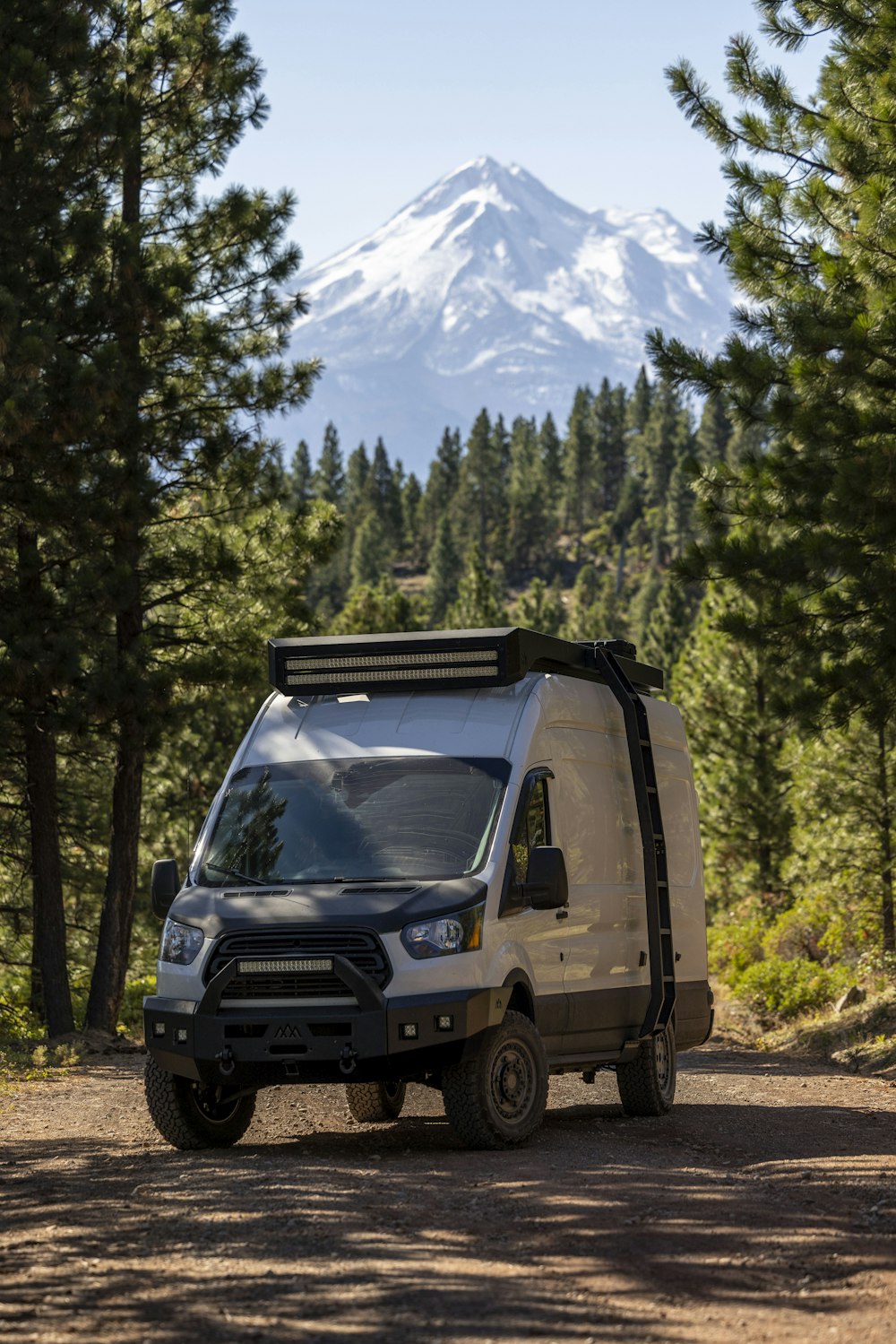 a van parked on a dirt road in front of a mountain