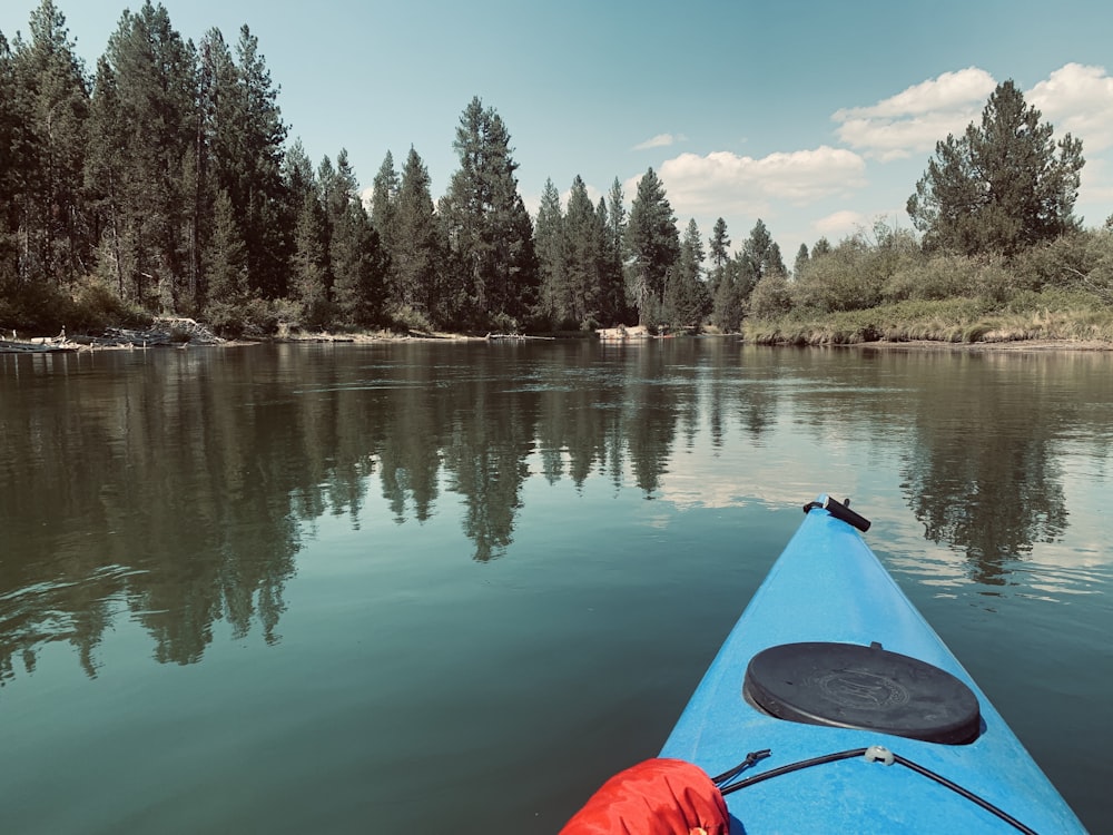 a blue kayak in the water with trees in the background