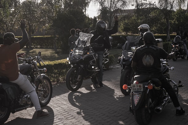 A group of smiling club members gathered around motorcycles at a sunny outdoor event.
