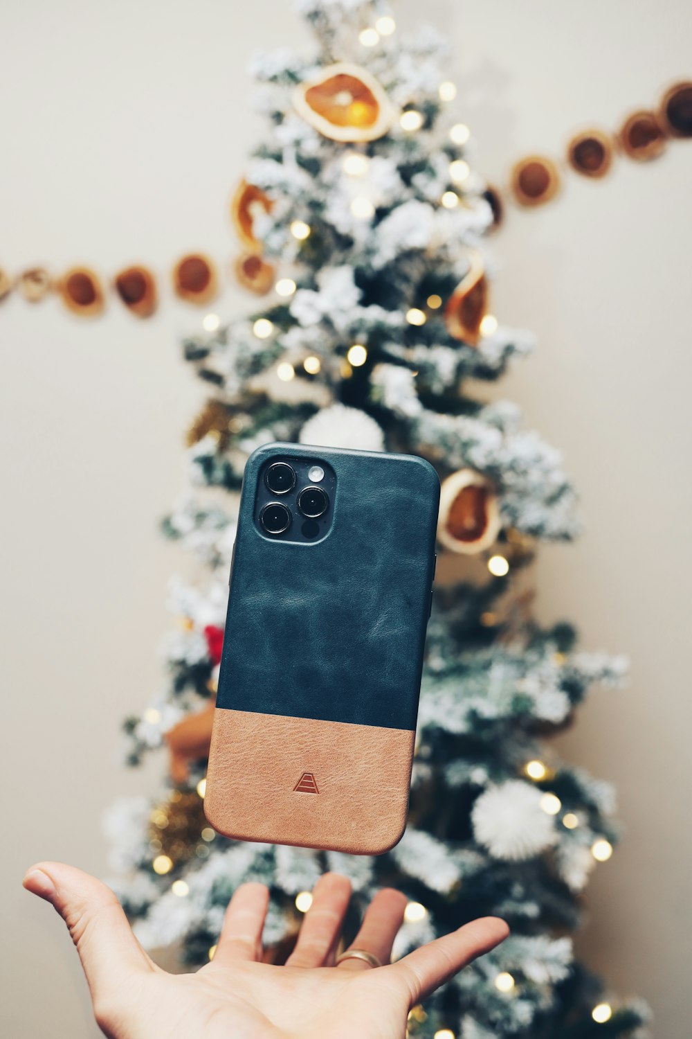 a person holding a cell phone in front of a christmas tree