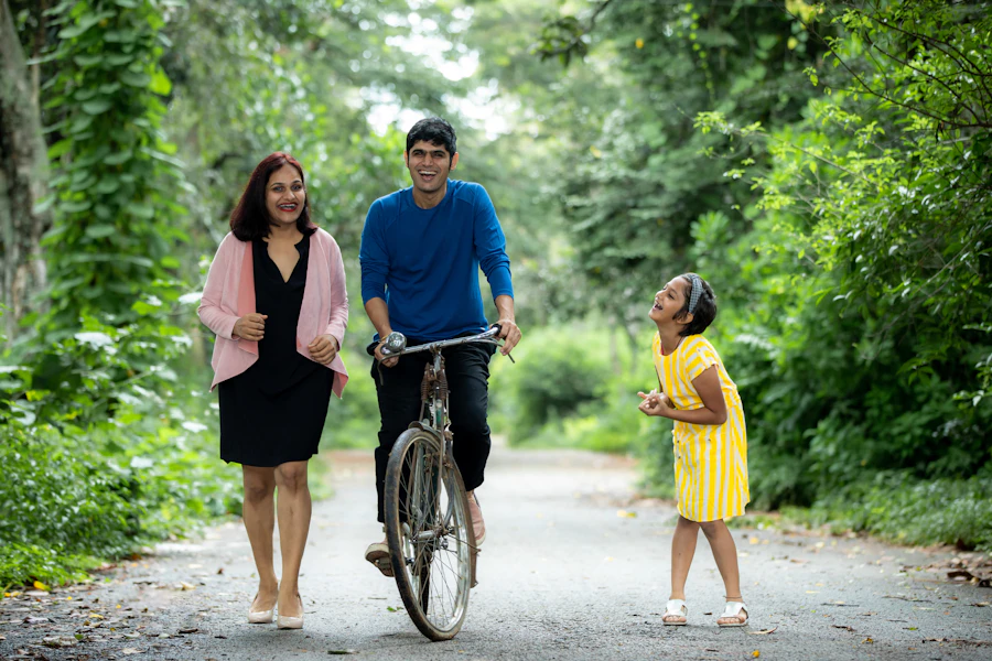 A family out together on a leafy lane, dad riding a bicycle beside mom and their daughter