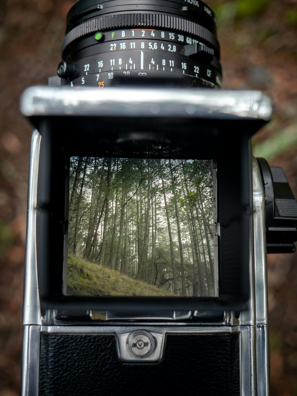 um close up de uma câmera com árvores no fundo