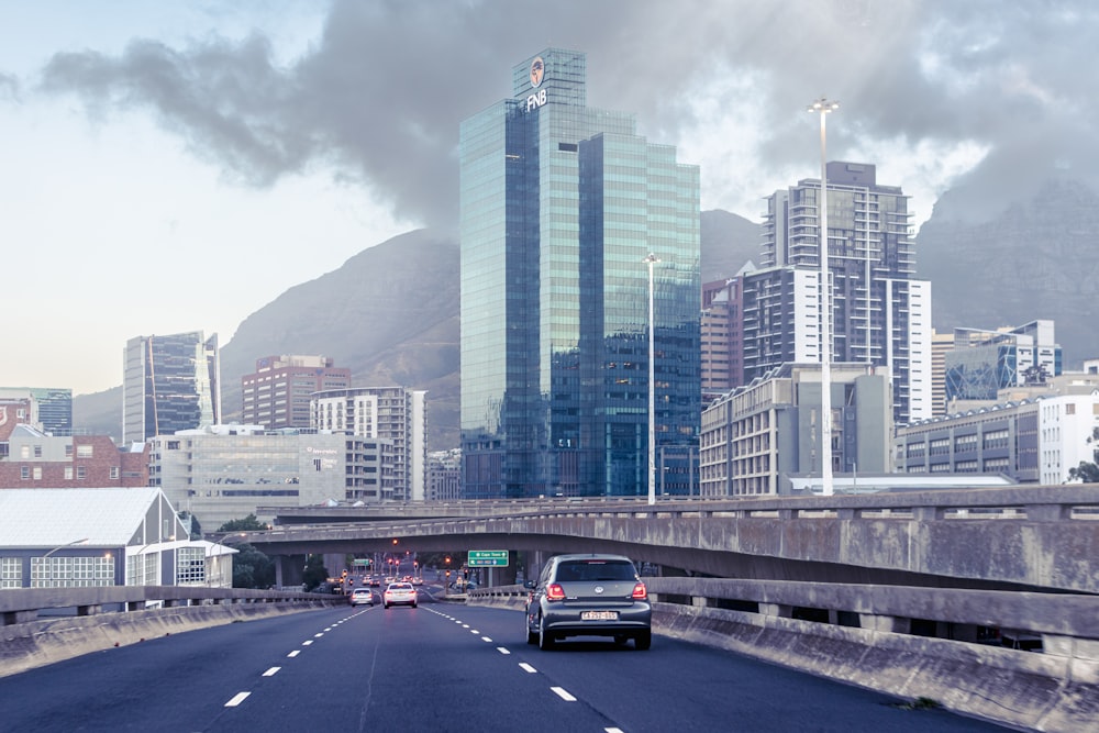 a car driving down a highway with tall buildings in the background