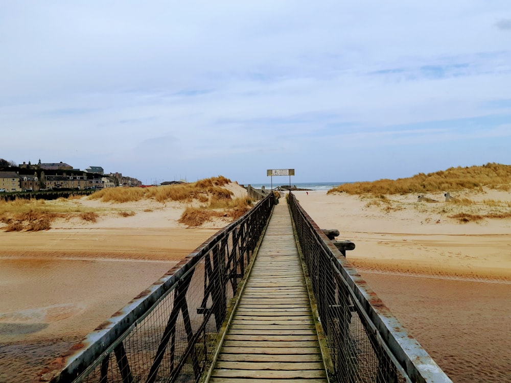 a wooden walkway leading to a sandy beach