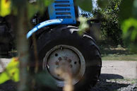 Close-up of a rugged tractor tire rolling over freshly plowed soil at sunrise.