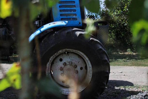 A close-up of a rugged tractor tire rolling through a muddy field at sunrise.