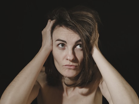 Woman experiencing symptoms of silent inflammation with hands on head, demonstrating chronic stress 