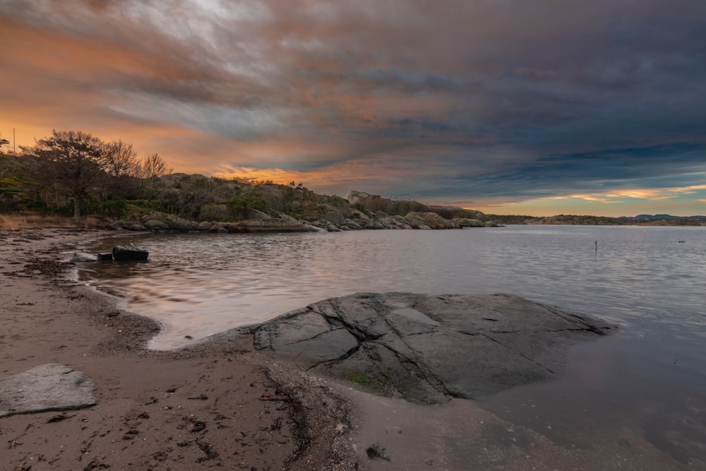 a large body of water with rocks in the foreground