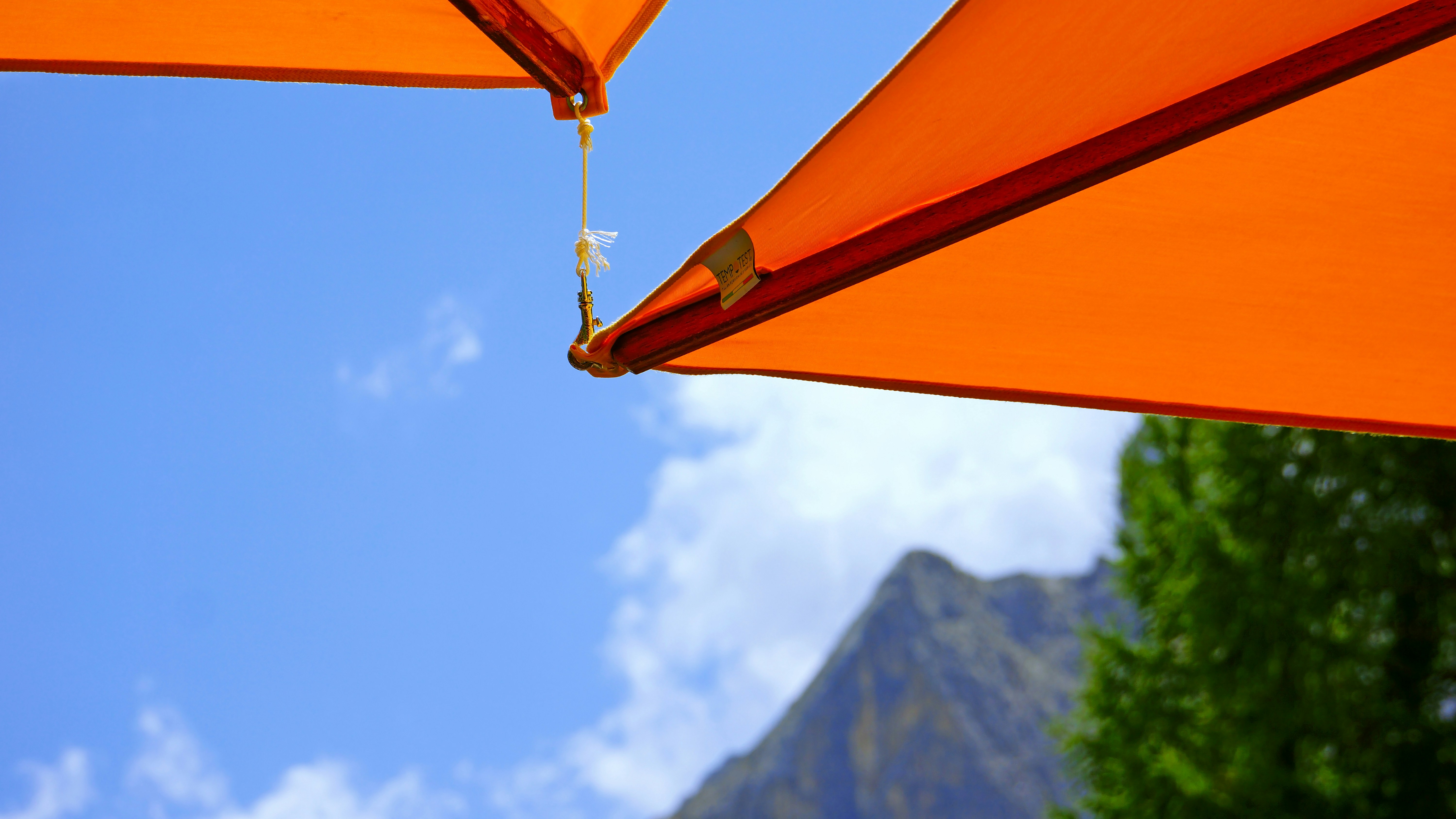 a close up of an orange umbrella with a mountain in the background