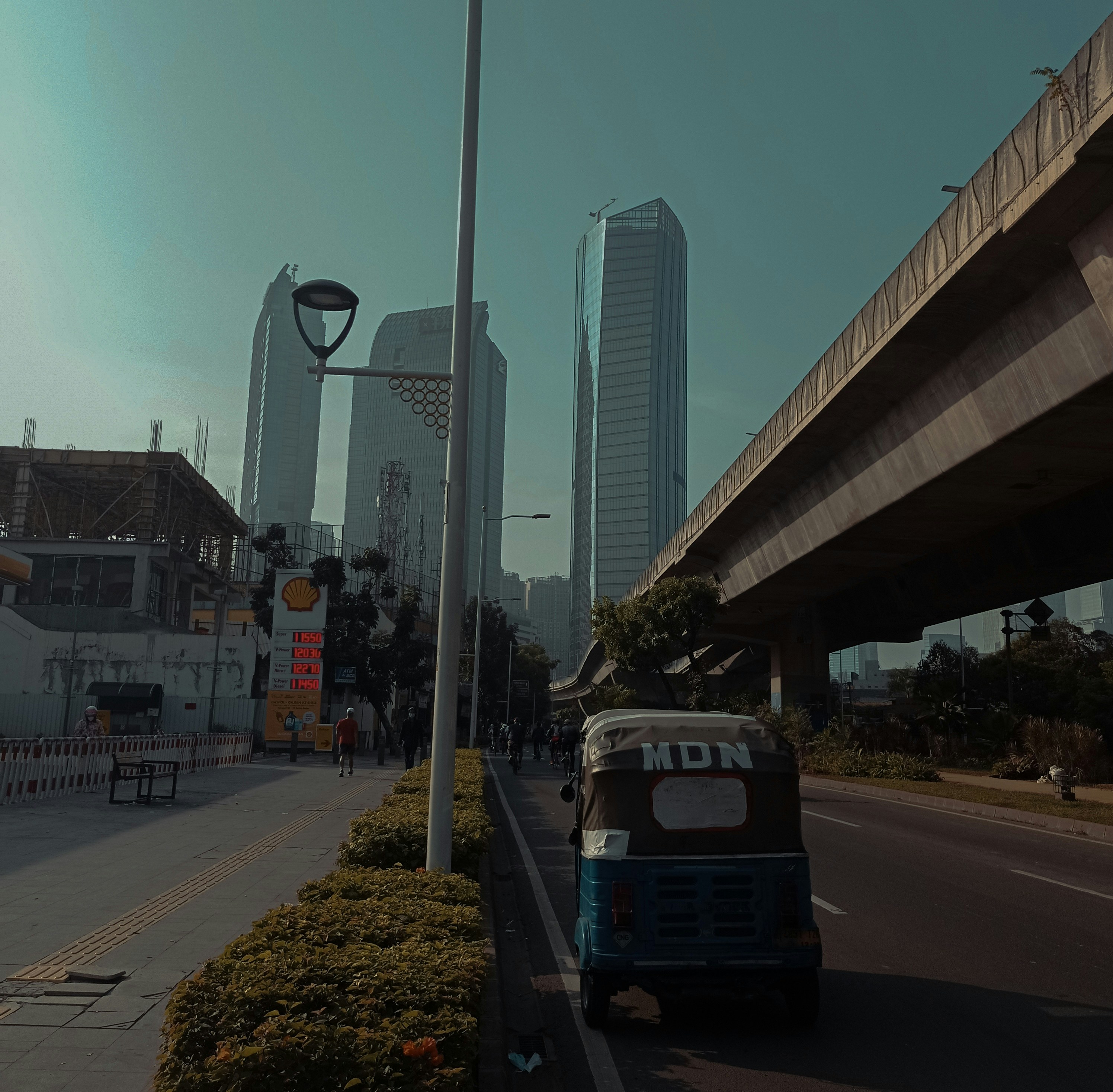 uma van azul e branca dirigindo por uma rua ao lado de edifícios altos