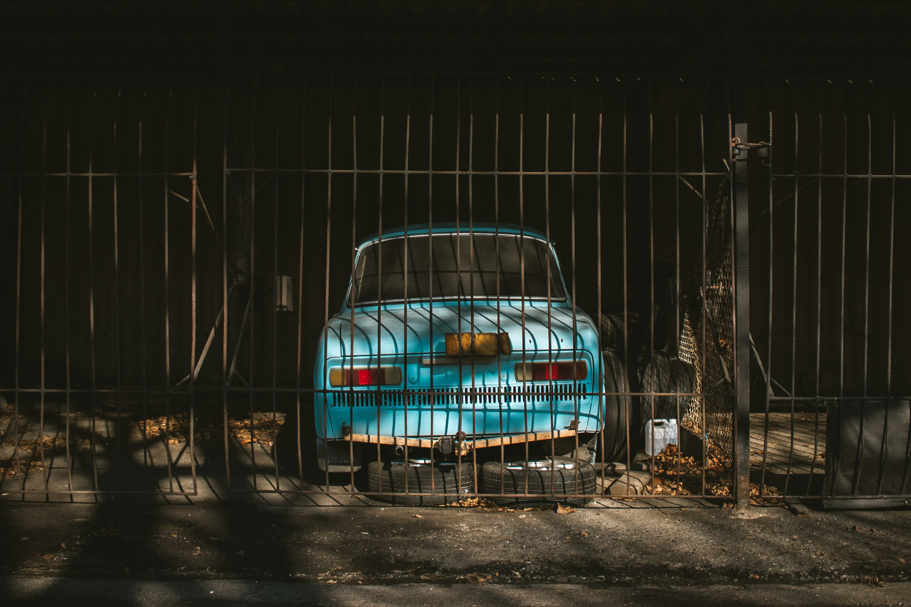 a blue car behind a metal fence