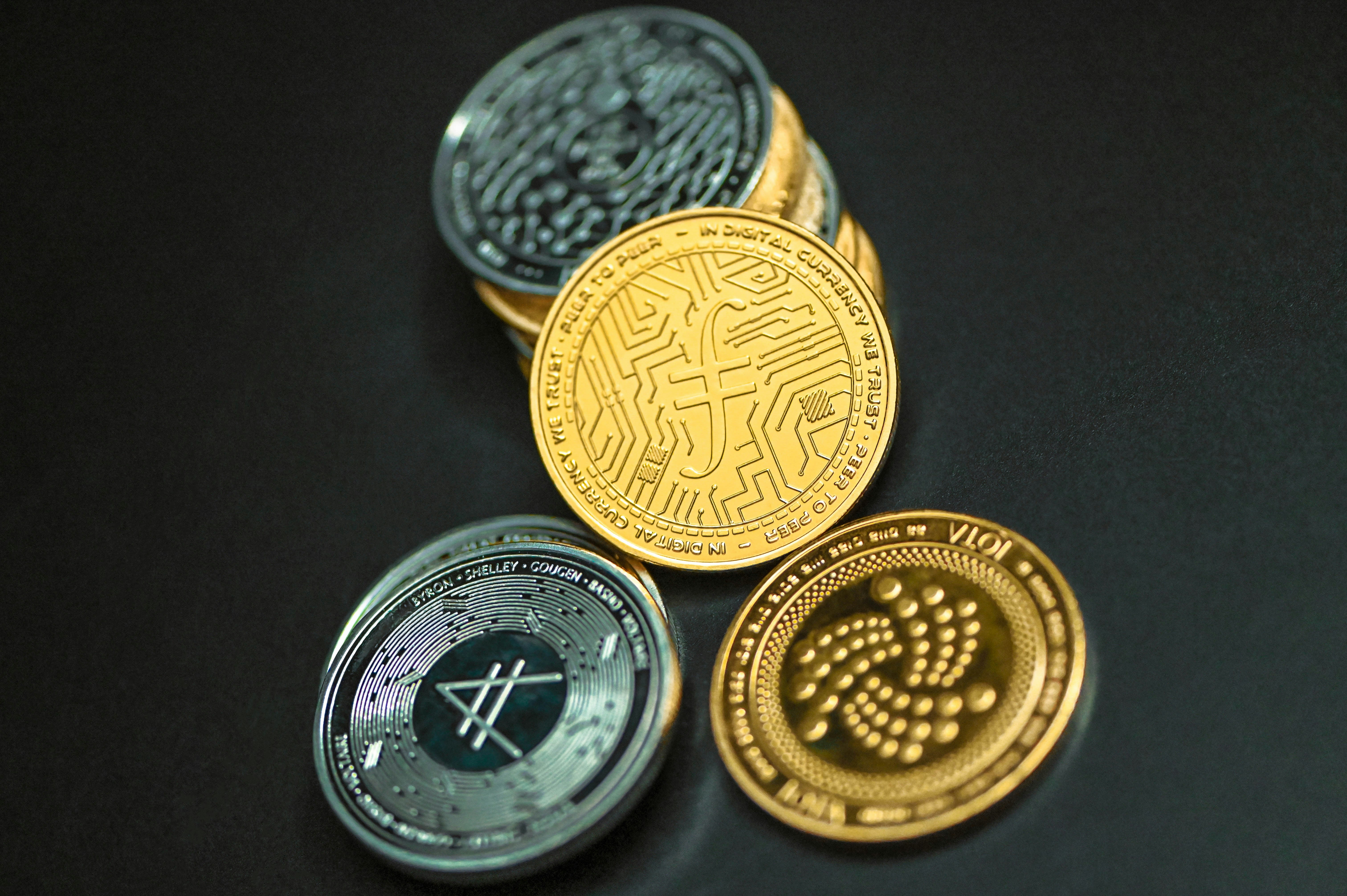 Filecoin, AMP coin, and IOTA coin together on a black surface