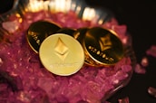 two gold coin sitting on top of a pile of pink crystals
