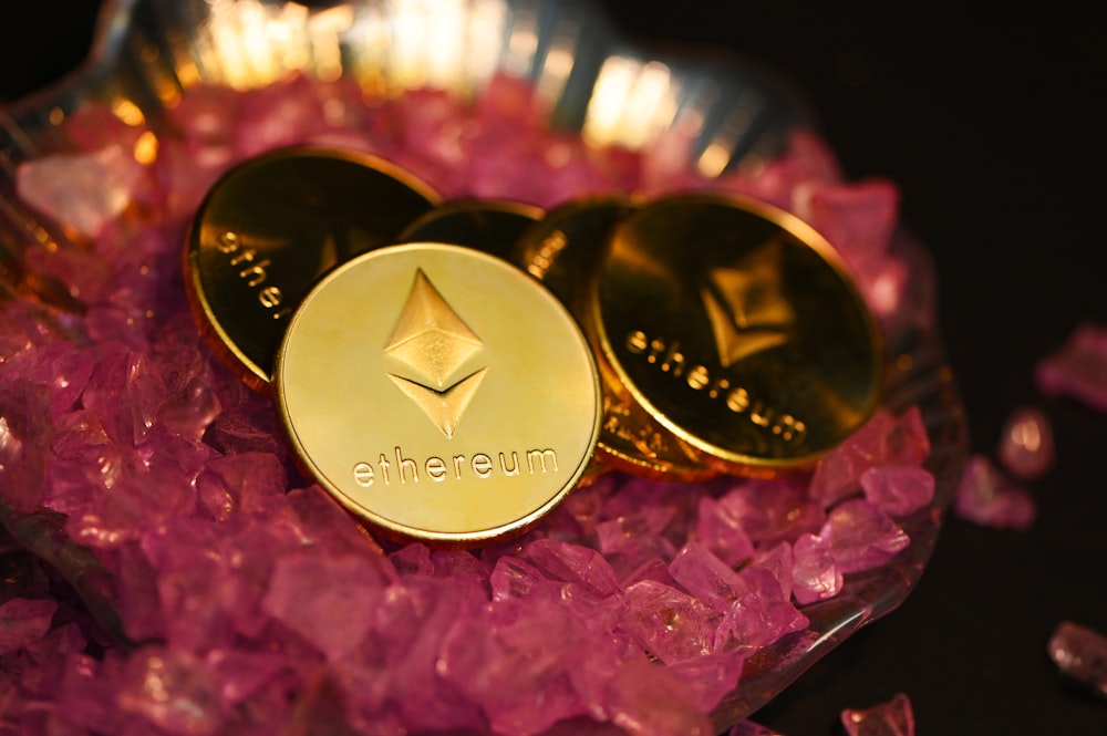 duas moedas de ouro sentadas em cima de uma pilha de cristais cor-de-rosa
